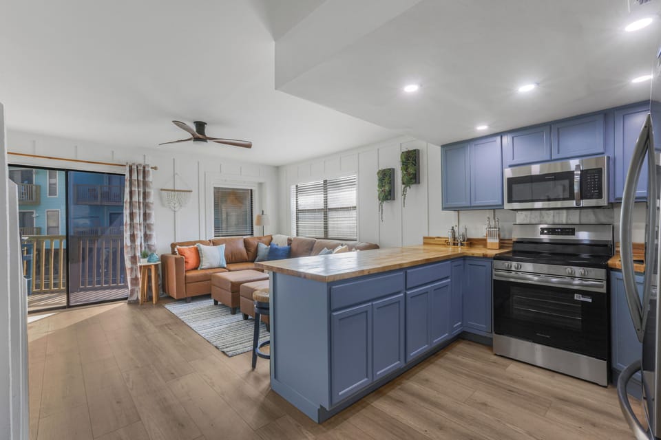 Bright open living space with stylish blue kitchen and private balcony access