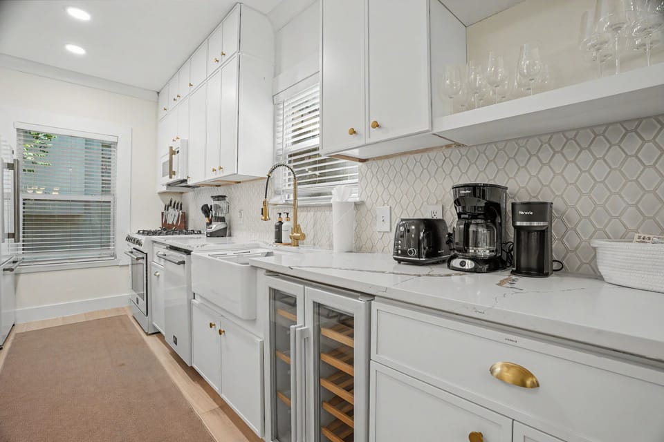 Bright designer kitchen with farmhouse sink, gas range, and wine coolers