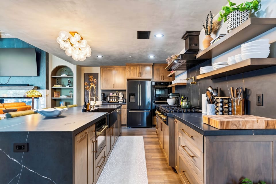 A spacious, well-equipped kitchen with a large island, warm wood cabinetry, dark finishes, and plenty of room to gather.
