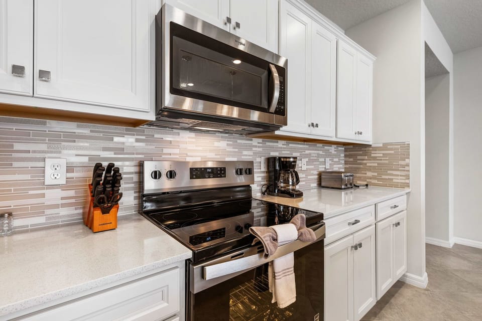 Cook with ease in this sleek chef's kitchen, complete with stainless steel appliances, subway tile backsplash, and crisp white cabinetry for a clean modern look.