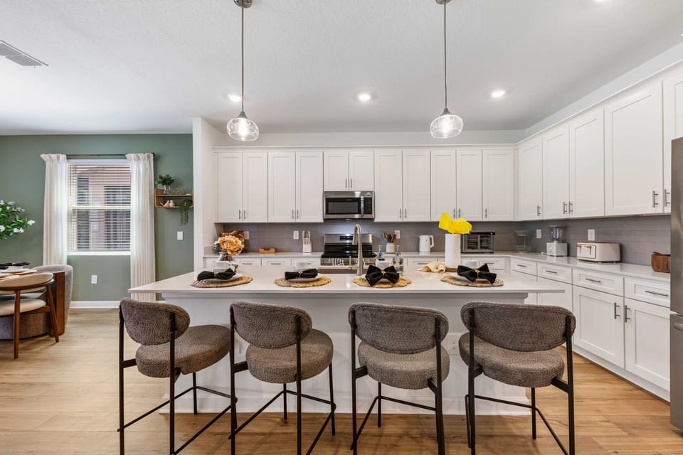 Gather at this bright modern kitchen with a large island, four comfy barstools, and sleek white cabinetry-perfect for casual meals and conversation.