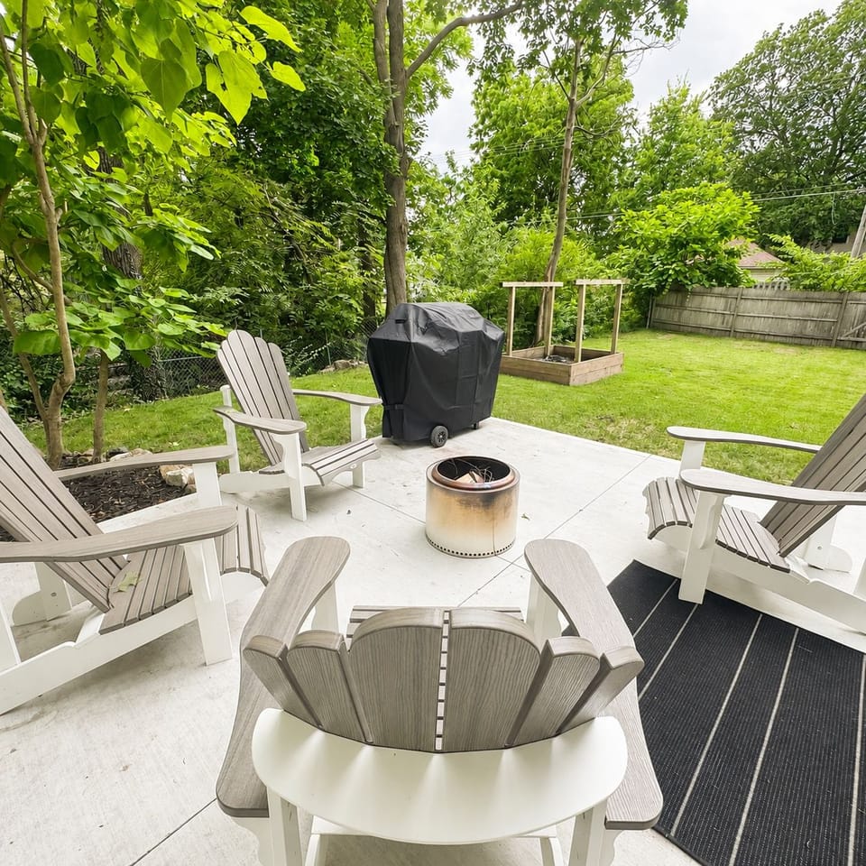 Private backyard patio with fire pit, grill, and lush green yard