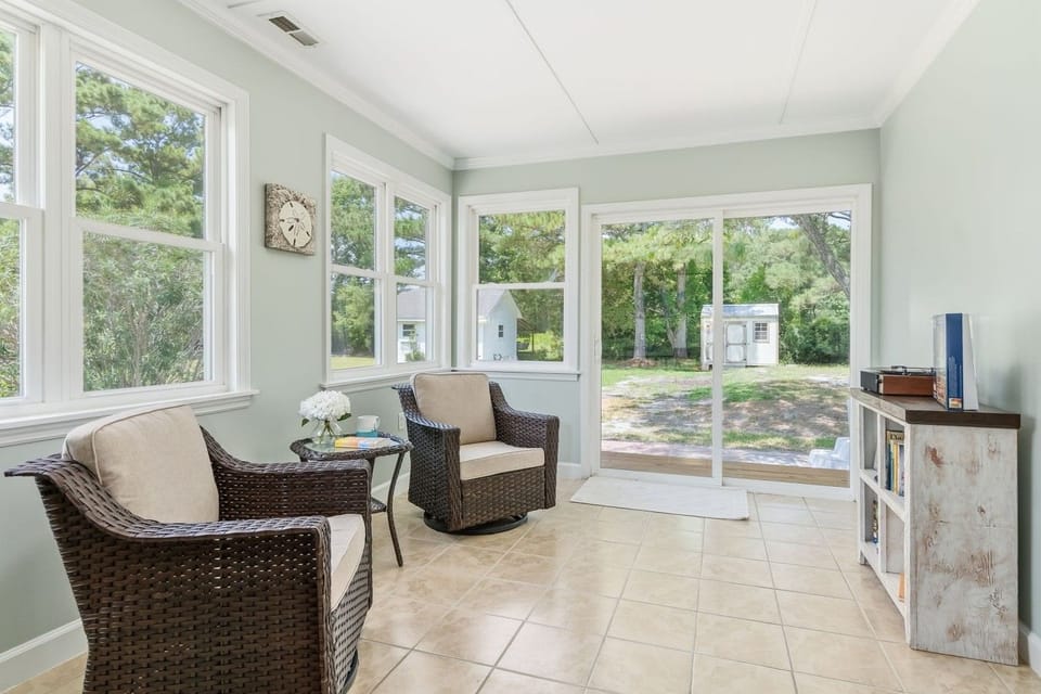 The sunroom lounge — sink into a chair with your morning coffee, then step straight out to the backyard and hot tub.