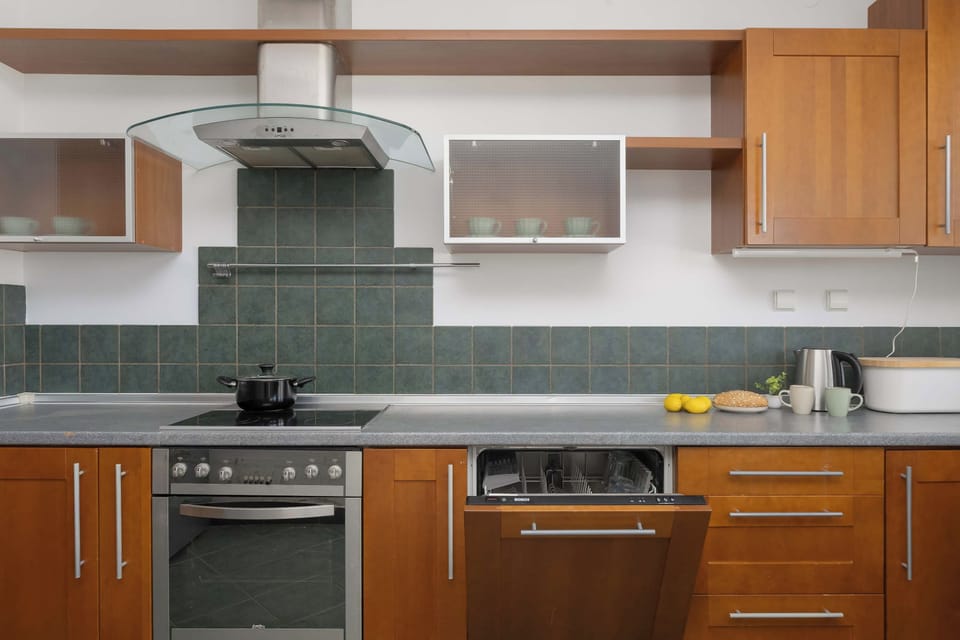A direct view of a kitchen workspace with an integrated oven and stovetop. Wooden cabinets provide ample storage space above and below the dark counter.