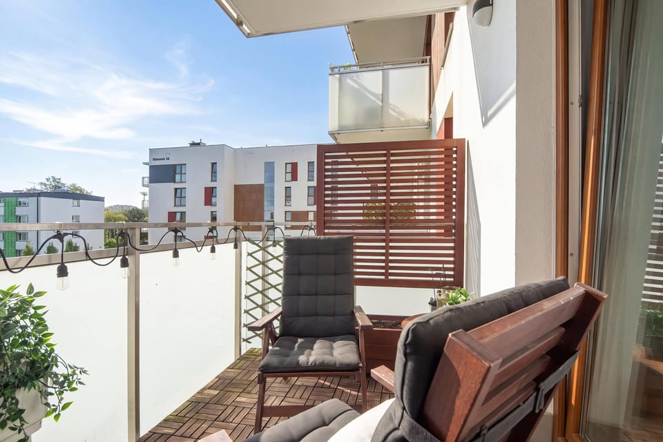 A furnished balcony with chairs and a small table overlooking the surrounding buildings.