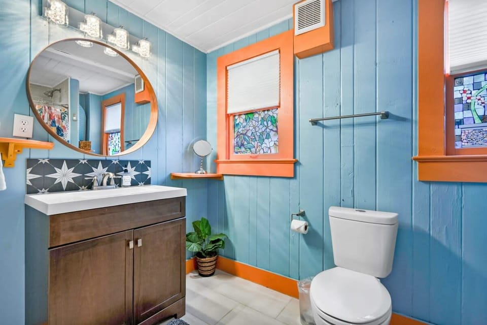 Stained-glass windows, a round mirror and wood vanity add bathroom charm, with a hair dryer and toiletries provided.