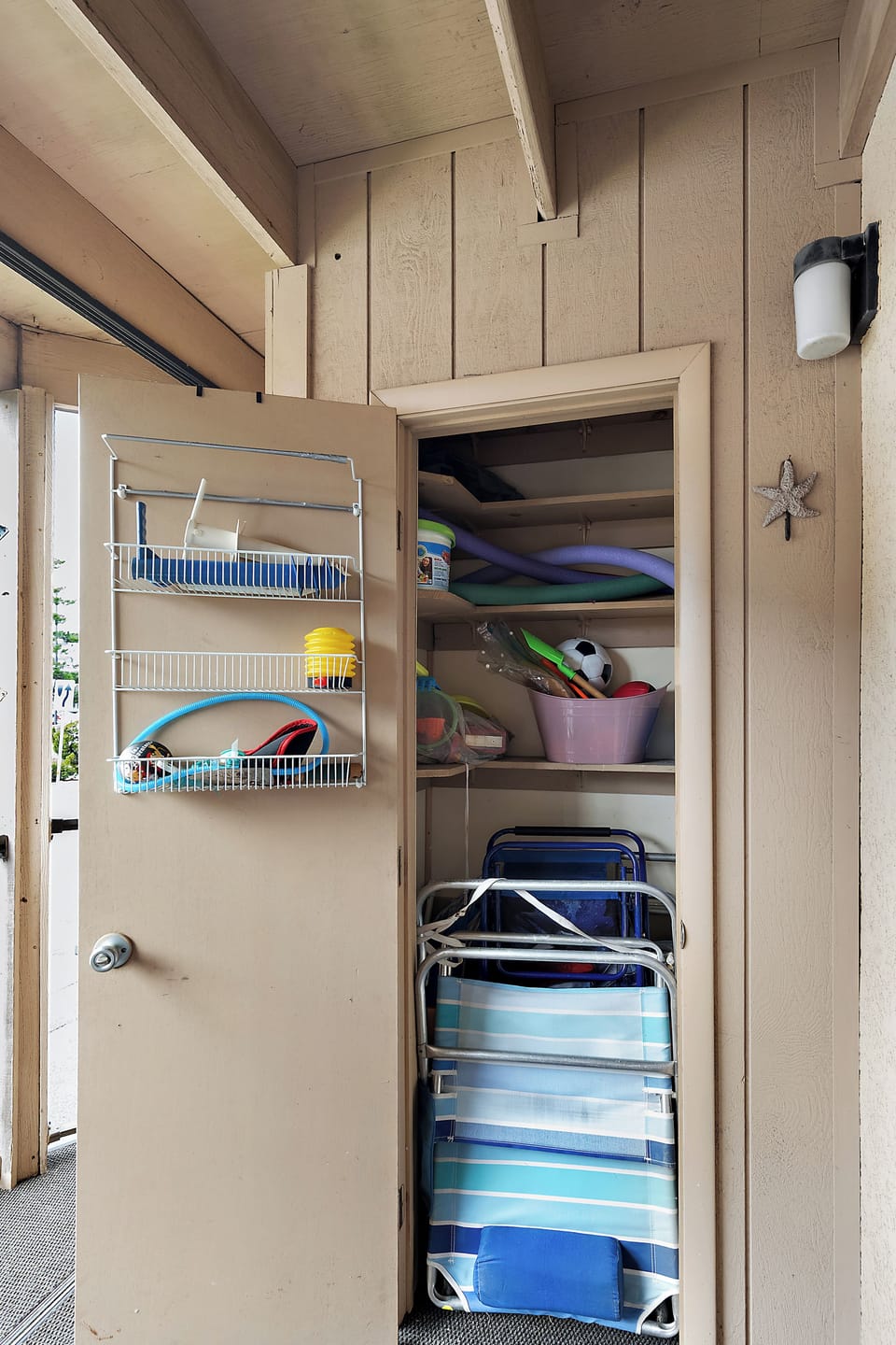 Patio closet with beach equipment: chairs, umbrella, cart, toys