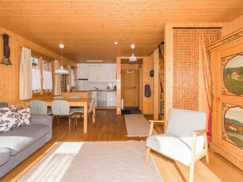 Spacious living area with sofa bed, dining table, and access to the kitchen and upper floor.
