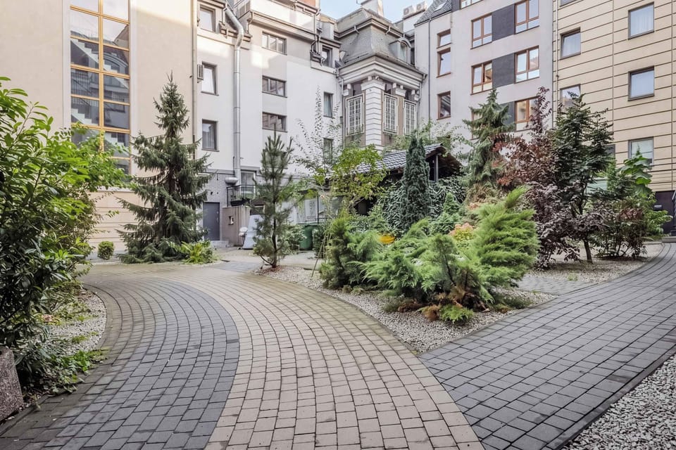 A view of the residential courtyard surrounded by modern apartment buildings and greenery. The paved pathway and landscaped areas create a peaceful outdoor environment.