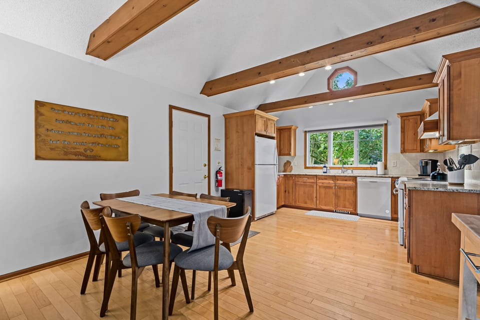 Bright wood-beam kitchen and dining area with forest views