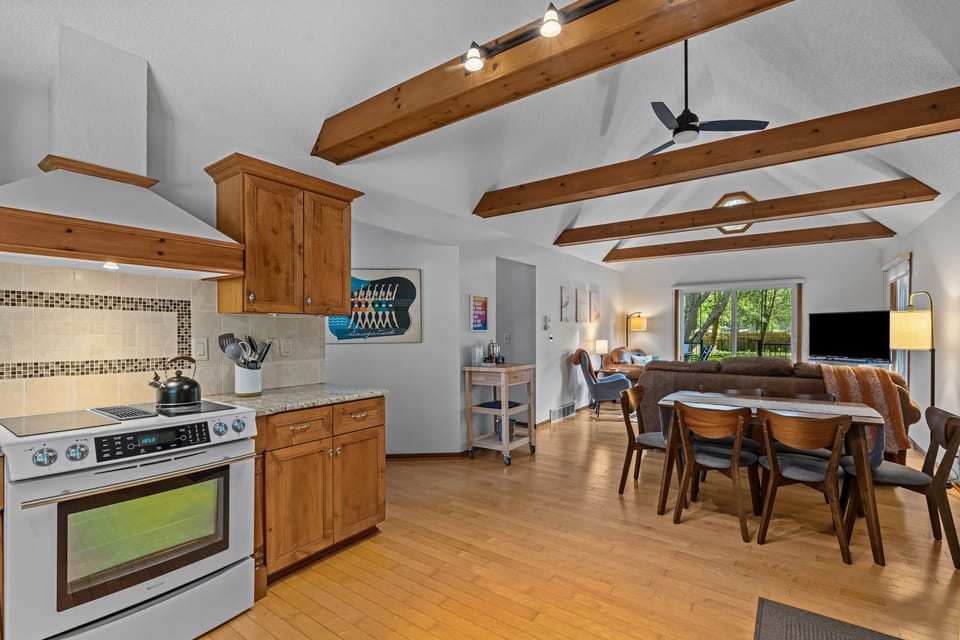 Bright open living space with vaulted ceilings, wood beams, and cozy seating