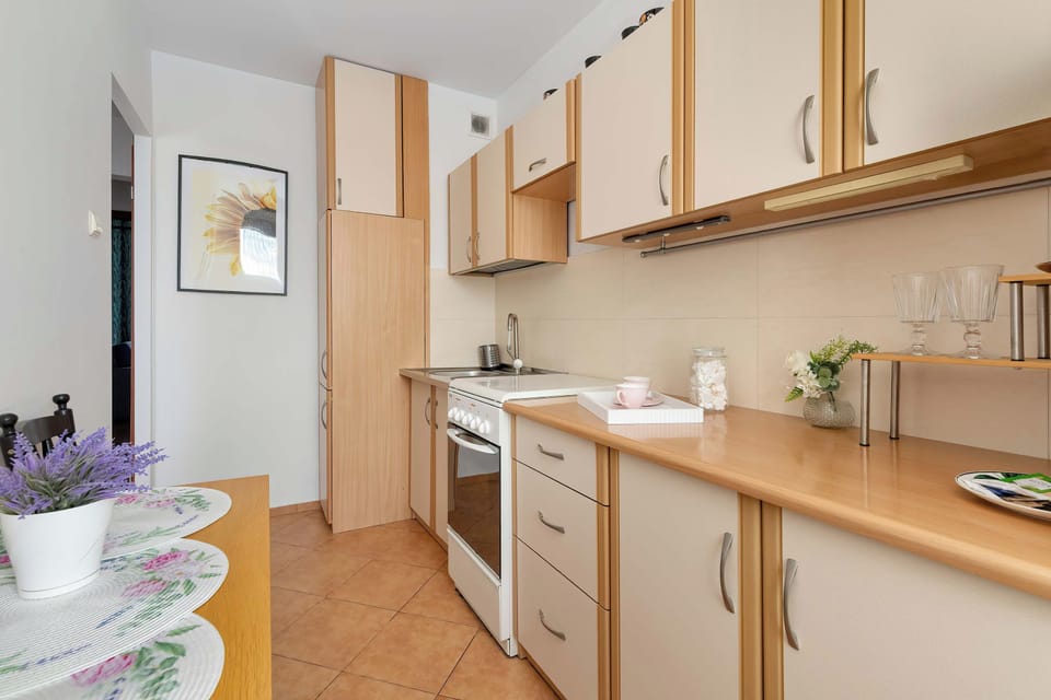 A compact bathroom with a sink, mirror, and light-colored tiled walls.