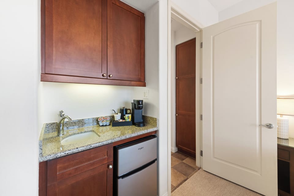Guest-ready wet bar with coffee station, mini fridge, and granite counter