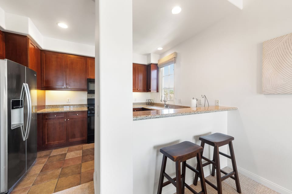 Bright kitchen with granite counters, breakfast bar, and stainless appliances
