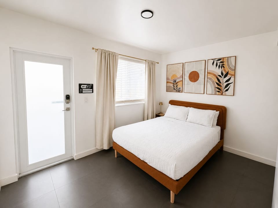 Bright modern bedroom with queen bed, natural light, and stylish decor