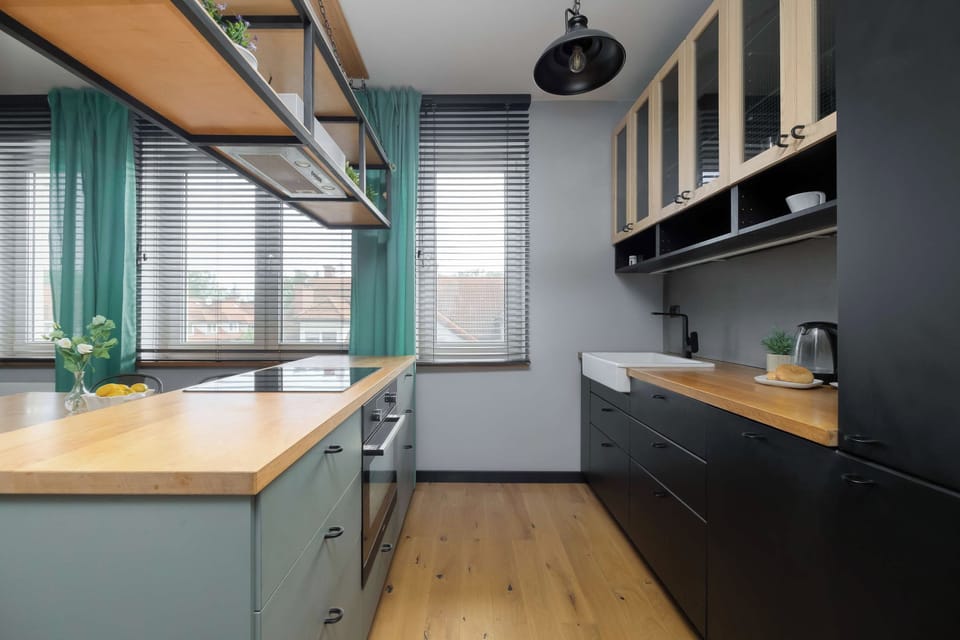 A view down the kitchen counter, showing a modern stovetop and ample, clean preparation space. The dark cabinetry provides a striking backdrop against the bright natural light from the window.