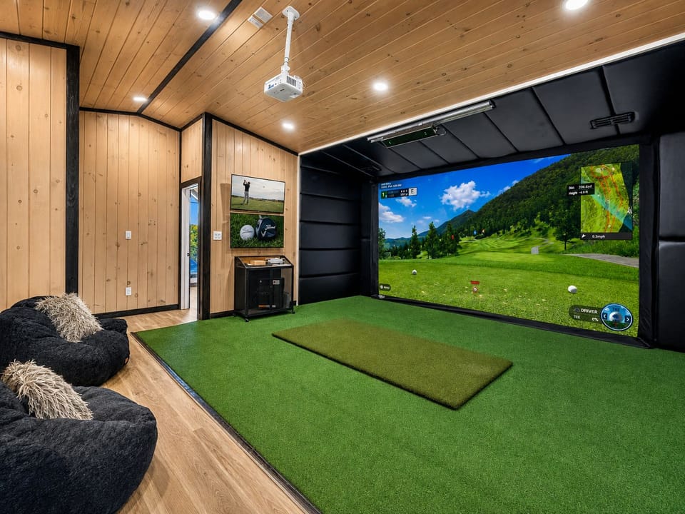 Private indoor golf simulator with cozy lounge seating and cabin-style design