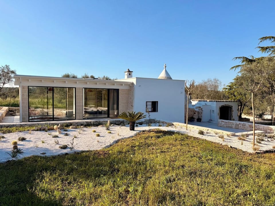 Garden view of the glass-walled living wing and trullo