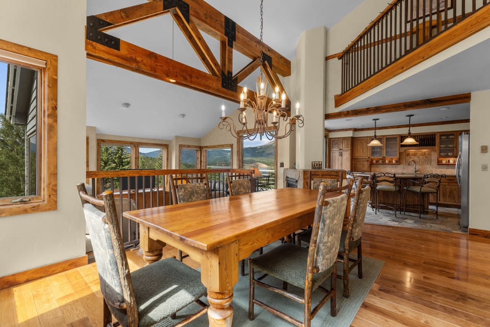 Gather around this stunning dining table beneath soaring timber-beamed ceilings while you take in breathtaking mountain views through expansive windows—a perfect space where your group can share meals and make memories together.
