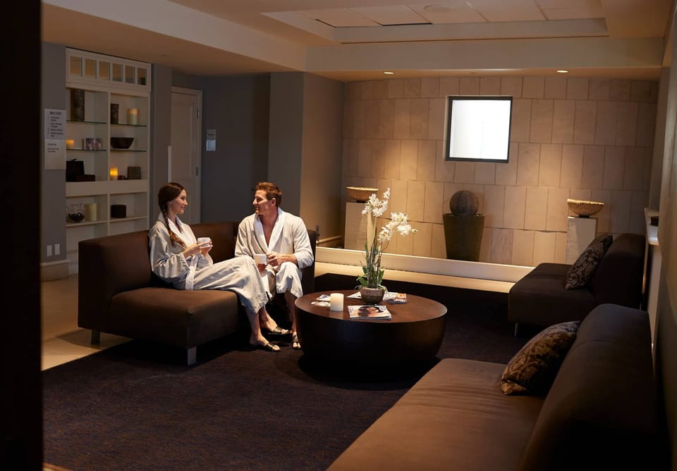 Two people in robes sitting in a relaxation area with drinks