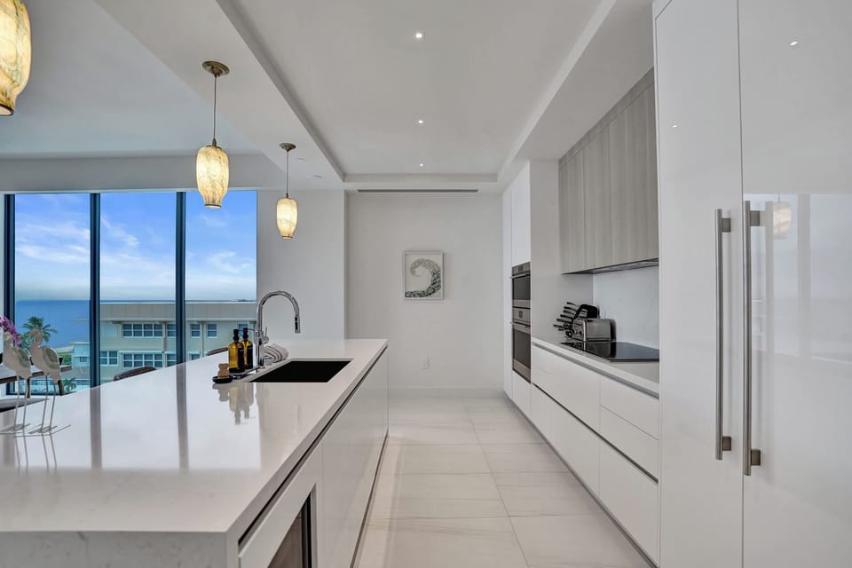 Kitchen island sink with a direct ocean view framed by floor-to-ceiling glass — cook with the sea in front of you.