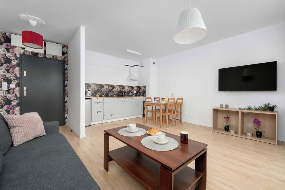 The living room layout includes a flat-screen TV mounted on the wall opposite the seating area.