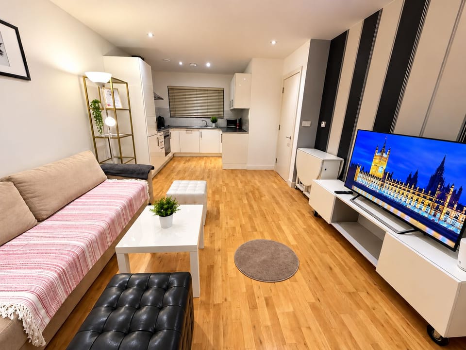 A spacious living room featuring a comfortable sofa, a flat-screen TV, and a dining area with a table, all open-plan with a modern kitchen for a welcoming and convenient stay.