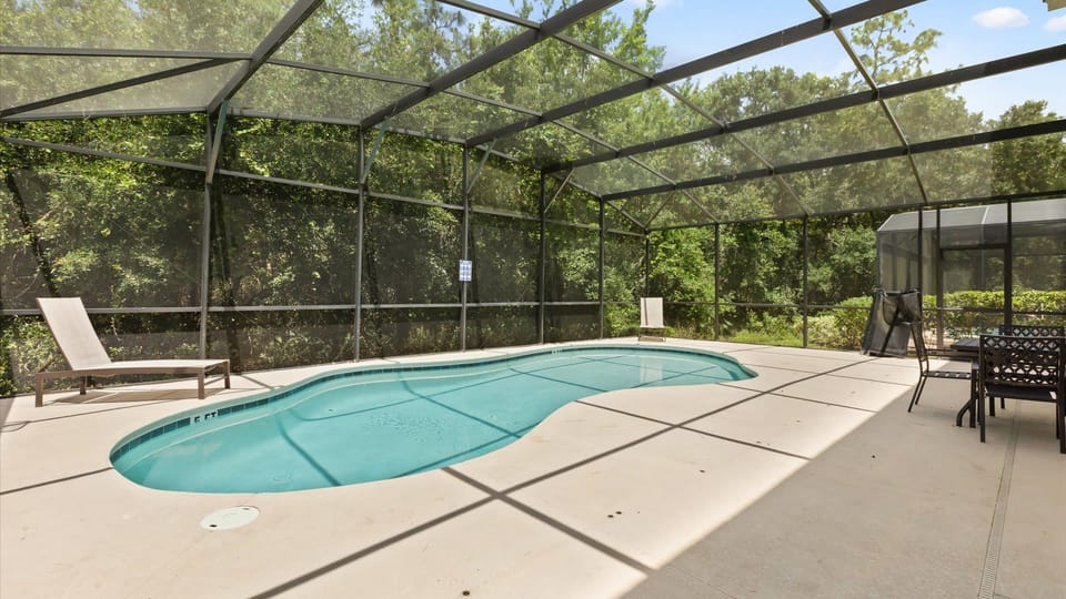Private screened pool deck with sunbeds and an outdoor dining area, perfect for poolside meals.