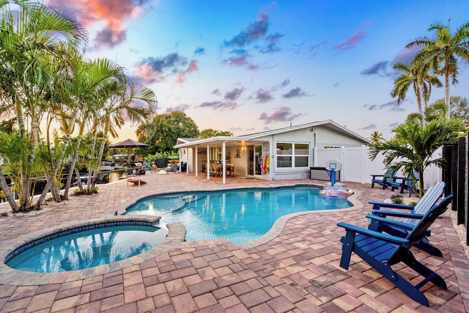 Resort-style backyard with pool, spa, palms, and sunny lounge seating