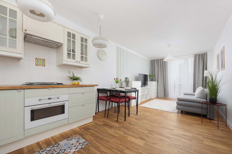 An open-plan kitchen and dining space with light wood cabinetry and a modern dining table. The kitchen is fully equipped with integrated appliances for daily convenience.