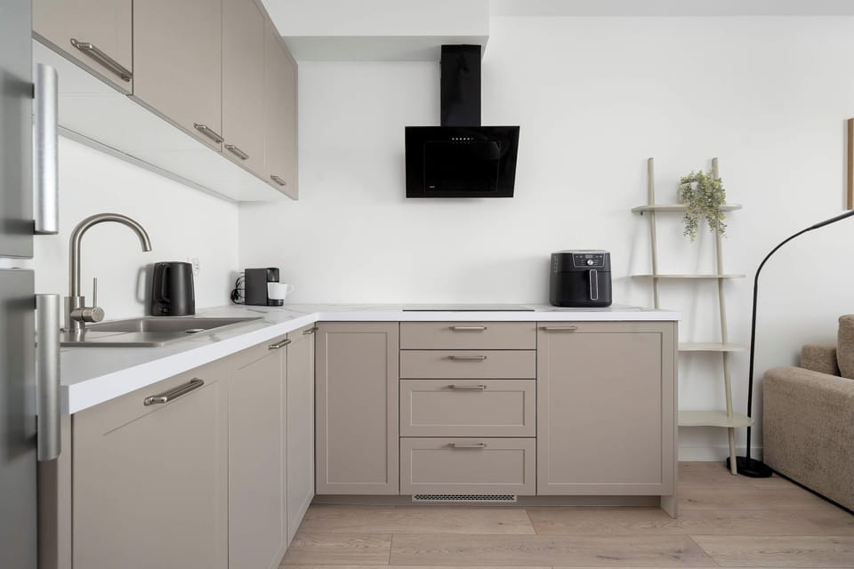 A modern white kitchen with built-in appliances, light cabinetry, and a compact dining area.