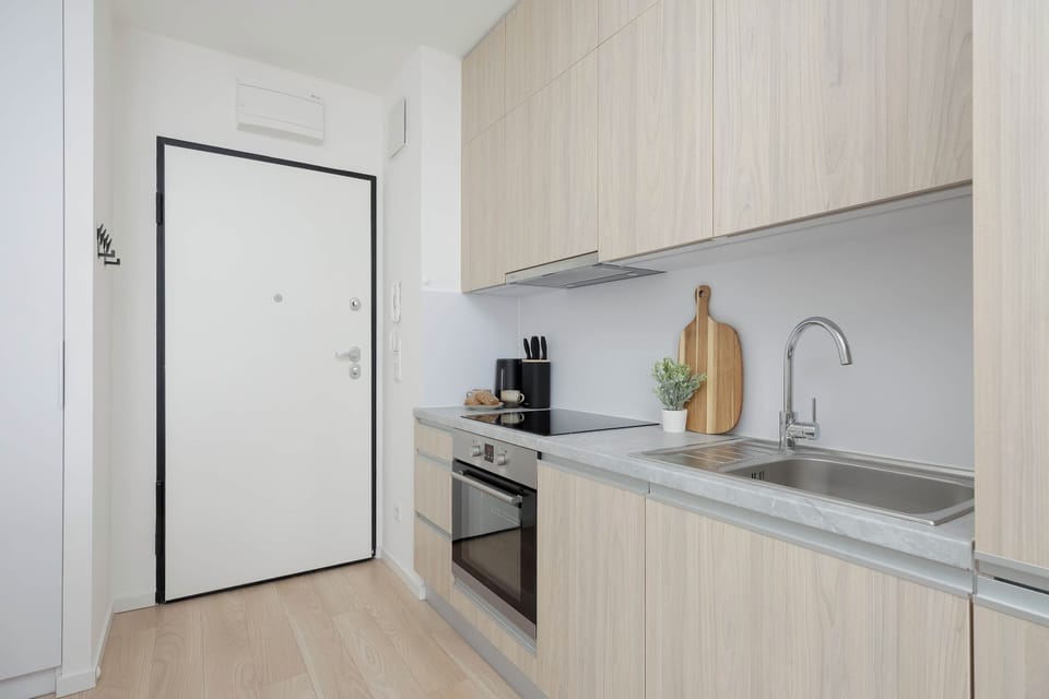 Well-lit kitchenette space showcasing light wood upper and lower cabinets alongside a sleek black oven unit.