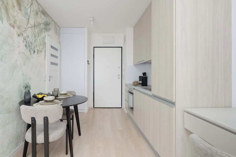 Open-plan kitchenette area adjacent to a dining space with a round table and modern chairs. 