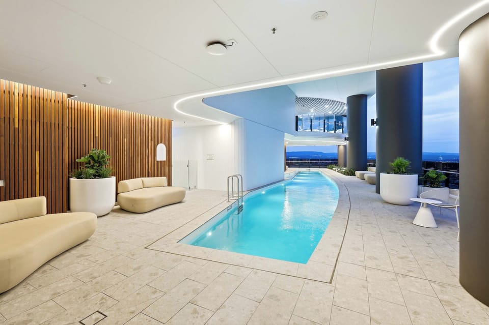 Luxury Lap Pool & Lounge Terrace
Unwind poolside on plush curved daybeds next to the illuminated lap pool, surrounded by ambient ceiling lighting and open skyline vistas.