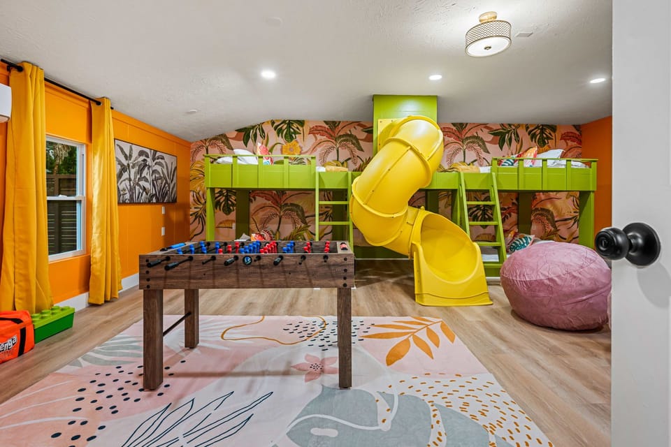 Playful kids’ room with bunk beds, foosball, and a fun yellow slide