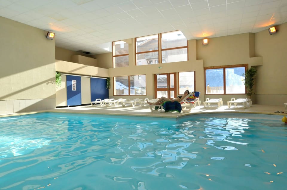 Indoor heated swimming pool with poolside loungers and large windows