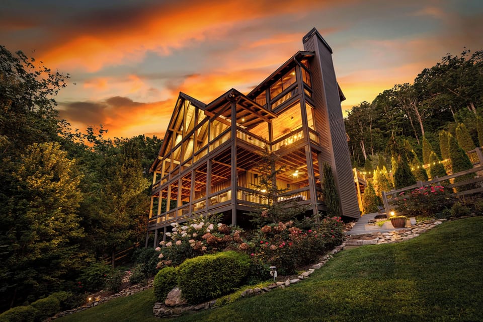 Tucked into the landscape, Bloom on the Ridge glows among the trees and flowers as evening falls. A mountain retreat designed to feel connected to its surroundings.