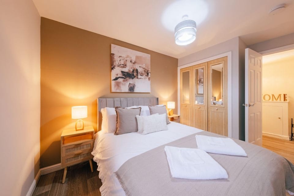 Cozy guest-ready bedroom with warm lighting and mirrored wardrobes