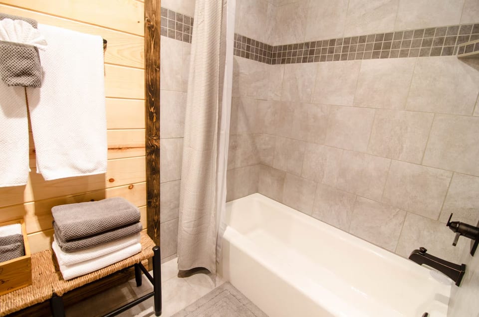 Cozy modern bathroom with tiled tub/shower and plush fresh towels