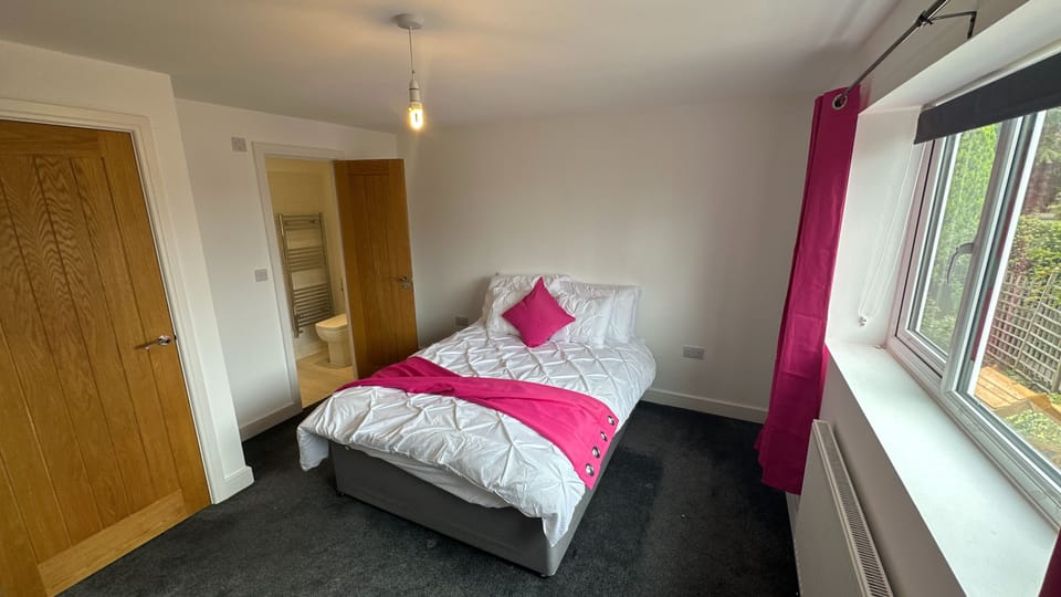 Bright ensuite double bedroom with garden-view window and modern styling