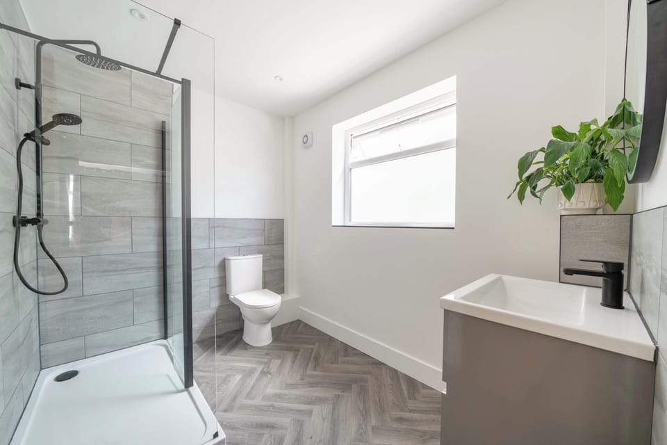 A contemporary bathroom showcasing a toilet, modern sink vanity, and glass shower.