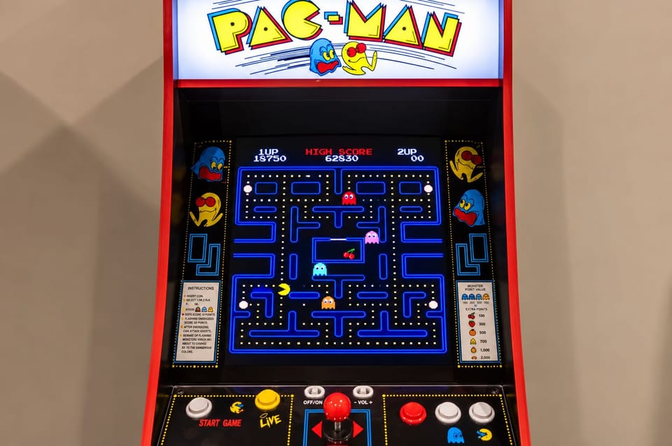 Close-up of a lit Pac-Man arcade machine with joystick controls.