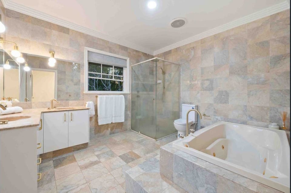 Luxurious ensuite bathroom equipped with stone tile finishes, a deep soaking tub, glass shower, and a modern vanity.
