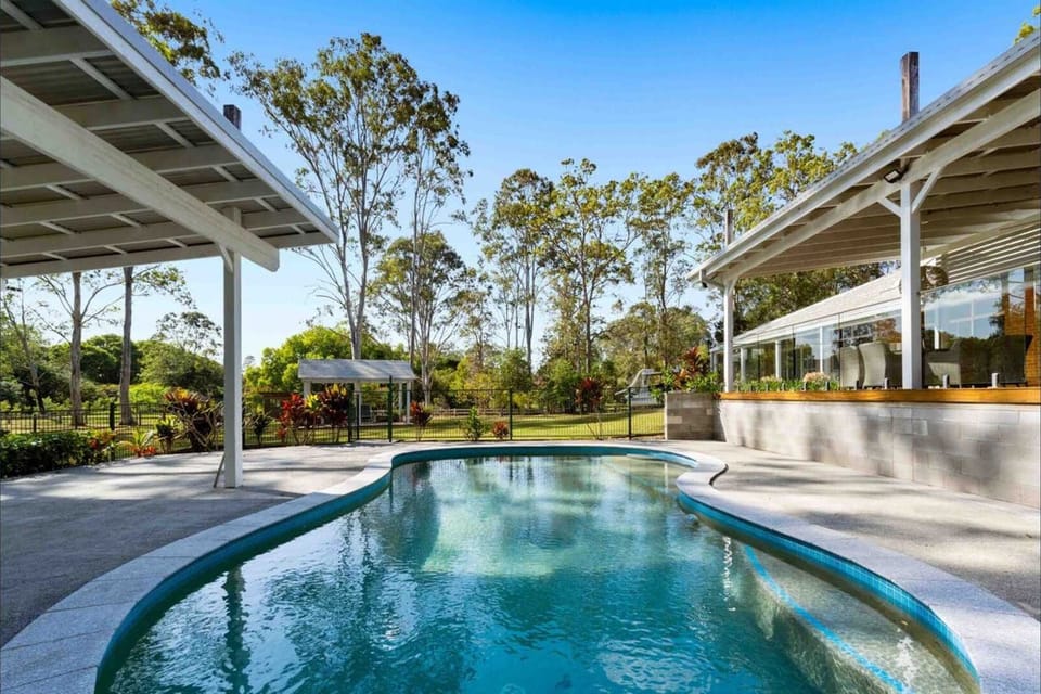 Alternative angle of the swimming pool highlighting its curved design and proximity to the house.   