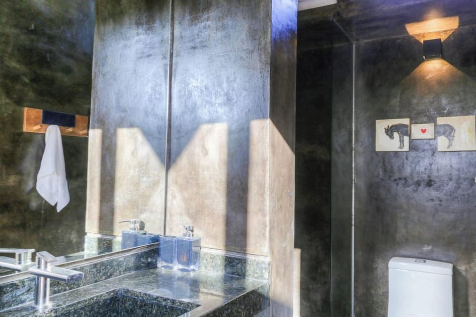 Second bathroom with dark stone walls and a glass sink.