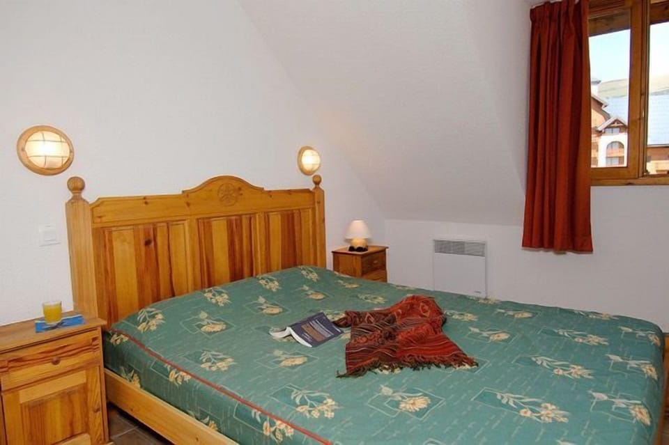 Bedroom under a sloped ceiling, with a wooden bed frame and floral bedding.