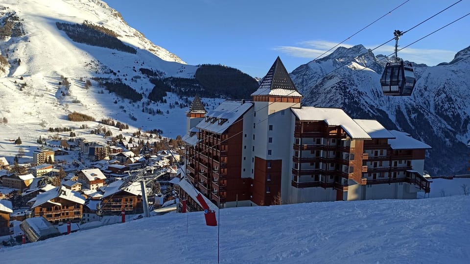 Snow-covered chalets and a gondola rising toward the pistes.