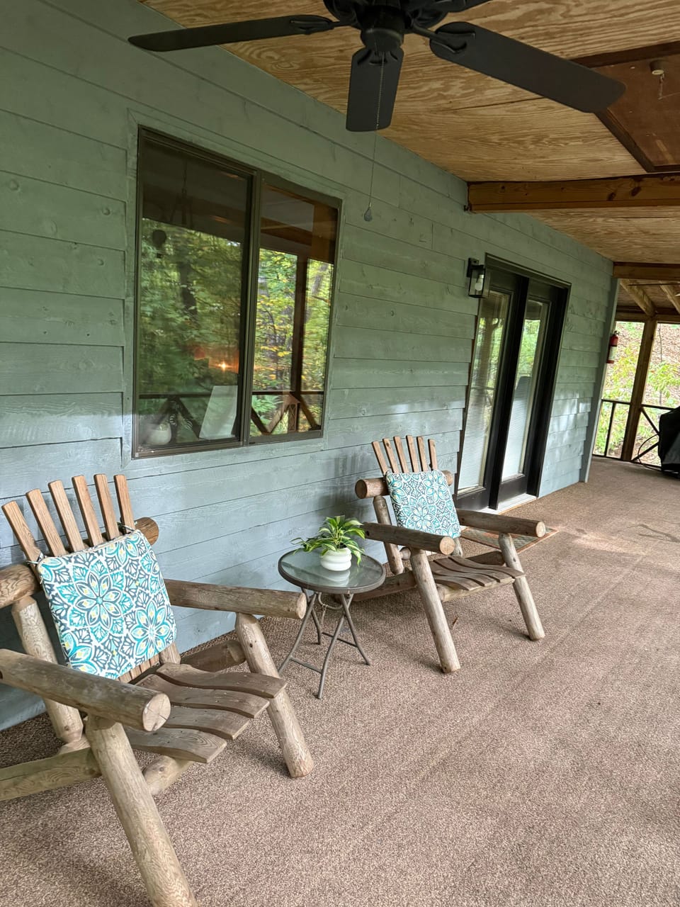 Covered porch featuring rustic log chairs and an overhead ceiling fan.