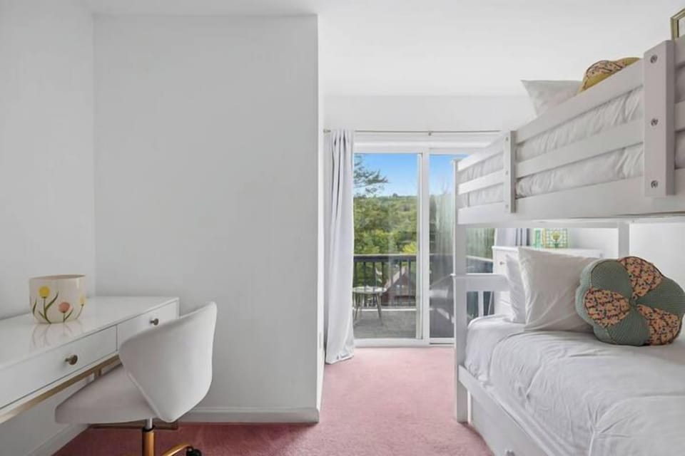 Bright bunk room with desk, balcony access, and peaceful treetop views