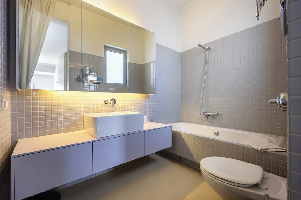 Bathtub, backlit mirror and warm lighting.